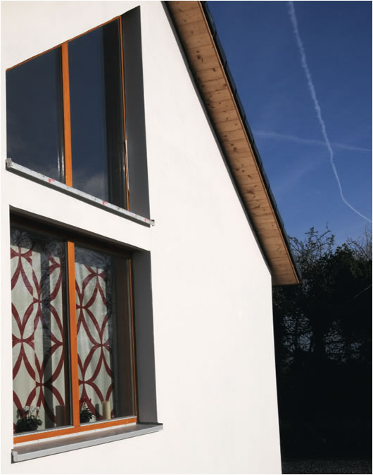 The external walls are finished with Heraklith cement fibre board under a concrete plaster render, and the draft-sealed windows are double-glazed units made from German larch and fitted with low-e glass