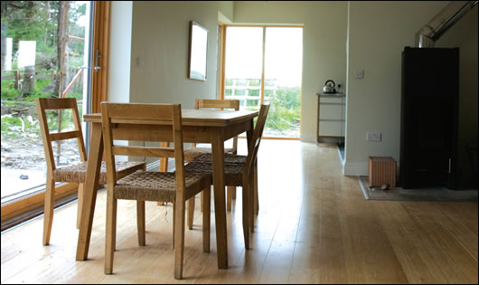 the open plan, bamboo- floored living room with Tonwerk masonry stove to right