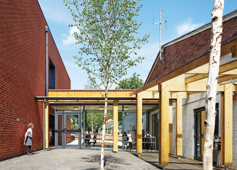 the new two-storey classroom block is linked by a glazed corridor to the original 1950s brick and concretepanelled school building