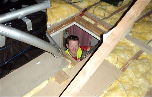 A contractor installing fibreglass insulation